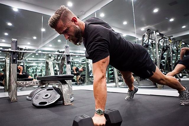 celebrity fitness trainer Magnus Lygdback works out at his gym with dumbbells