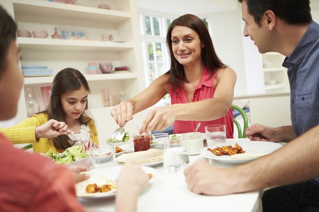 Hispanic Family Sitting At Table Eating Meal Together