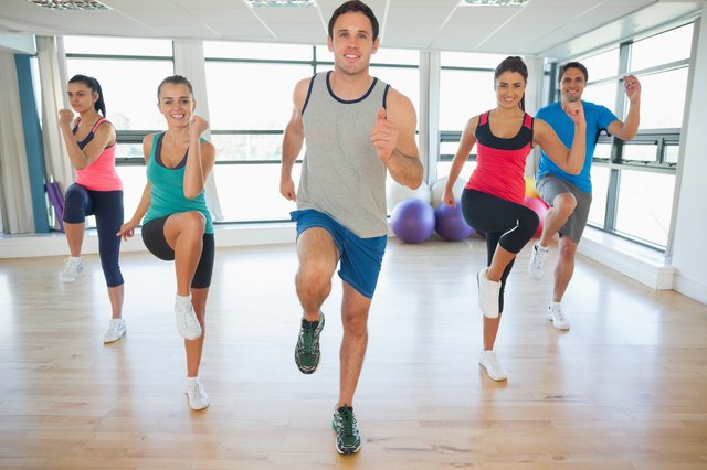 Full length of fitness class and instructor doing pilates exercise