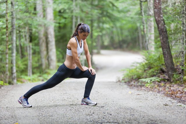 Middle aged woman stretching on dirt road