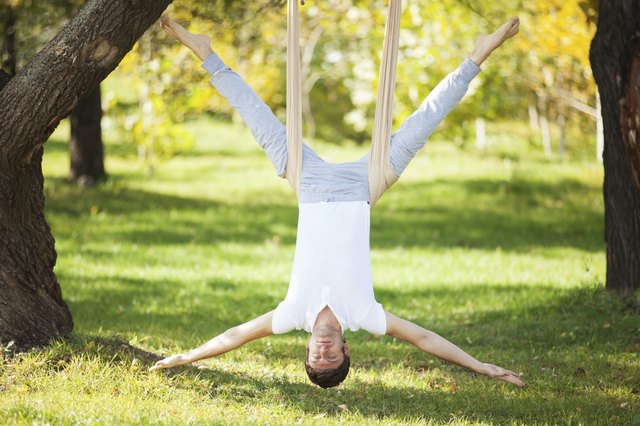 Anti-gravity Yoga, man doing exercises in the park