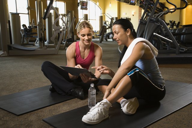 Adult female with personal trainer at gym.