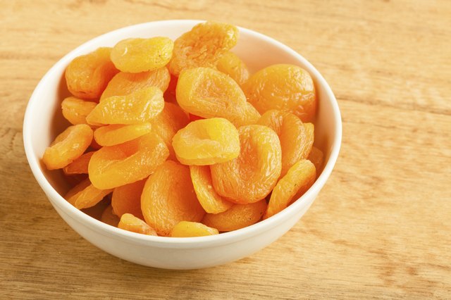 Bowl of dried apricots on wooden table background.