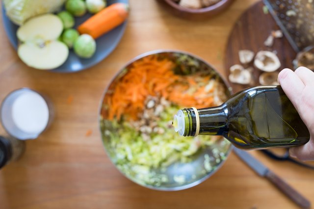 Pouring olive oil from bottle onto salad