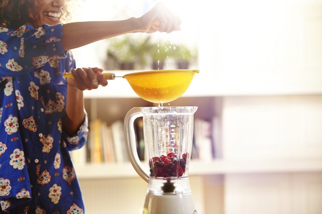 Woman squeezing an orange while making a smoothie.